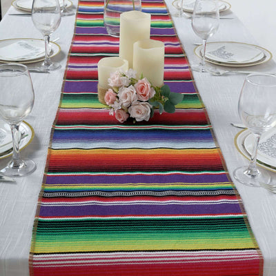 Colorful striped table runner with candles and flowers on a dining table.