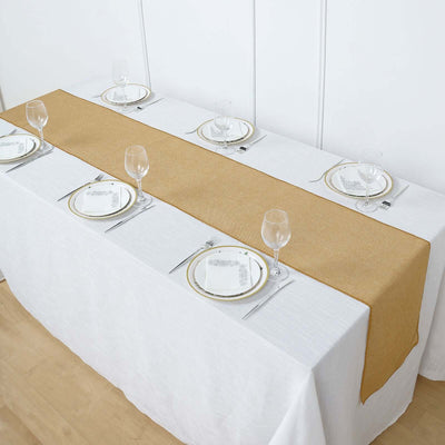 Elegant gold table runner on a white table setting with glassware and plates.