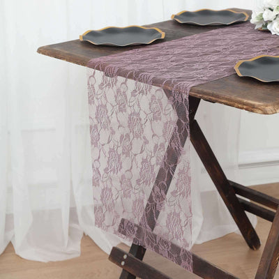 Lace table runner in mauve on a wooden table with black plates.