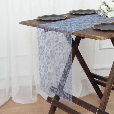 Blue lace table runner on a wooden table with black plates and floral decor.