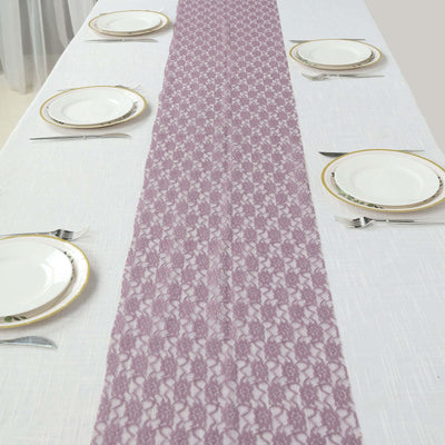 Purple lace table runner on a white table with dinner plates and utensils.
