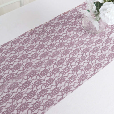 Lavender lace table runner on a white table with a vase of flowers.