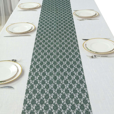 Green lace table runner on a white table setting with plates and cutlery.
