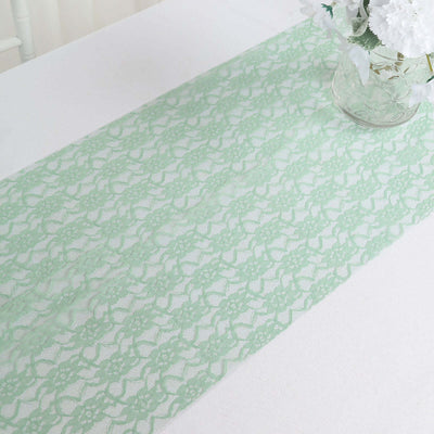 Green lace table runner on a white table with a vase of flowers.