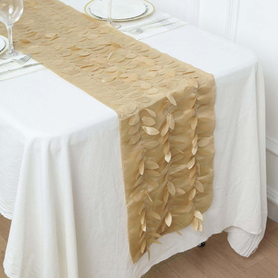 Gold leaf table runner on a white table setting with plates and glasses.
