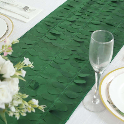 Green leaf table runner on a dining table with elegant place settings.
