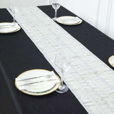 Elegant table runner on a black table with plates and glasses.
