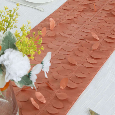 Peach table runner with leaf design on a dining table setting.