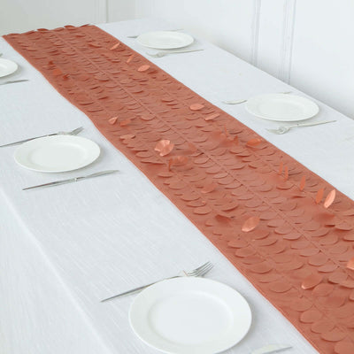 Copper leaf table runner on a white table setting with plates and cutlery.