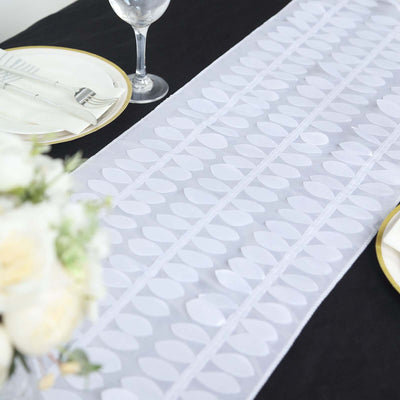 White table runner with leaf design on a black table setting.