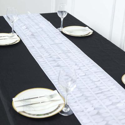 White table runner on a black table with plates and glasses set for dining.