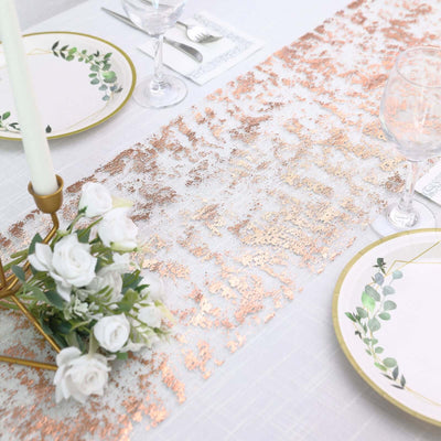 Elegant rose gold table runner with floral arrangements and tableware.