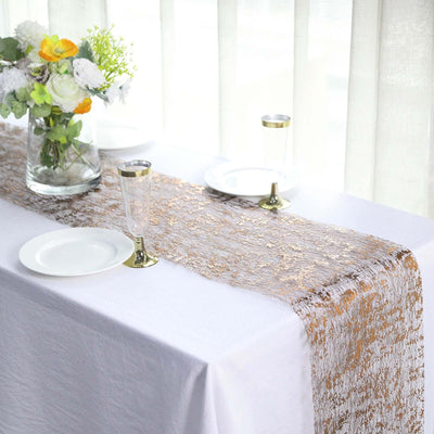 Elegant gold lace table runner on a white table with plates and glasses.