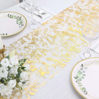 Elegant gold and white table runner with floral plates and wine glasses.