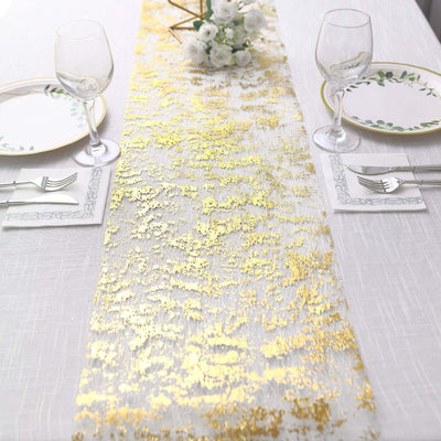 Elegant gold and white table runner on a dining table with plates and glasses.
