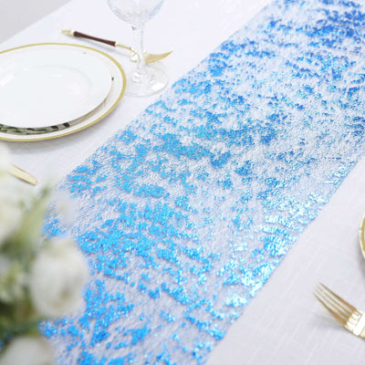 Blue sequin table runner on a white table setting with plates and cutlery.