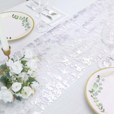 Elegant table setting with a silver sequin runner and floral centerpiece.