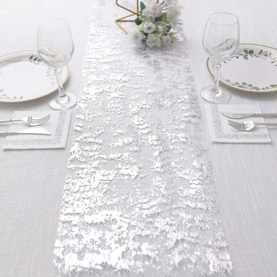 Silver sequin table runner on a dining table with elegant place settings.