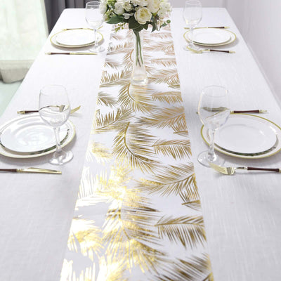 Gold palm leaf table runner on a dining table with glassware and plates.