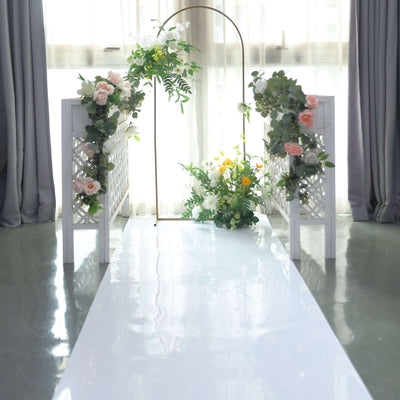 Decorative wedding arch with flowers and greenery in a bright indoor setting.