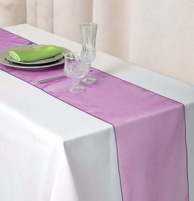 Purple table runner on a white table with glassware and green napkins.