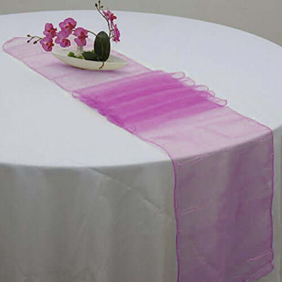 Pink sheer table runner with decorative flowers on a white table.