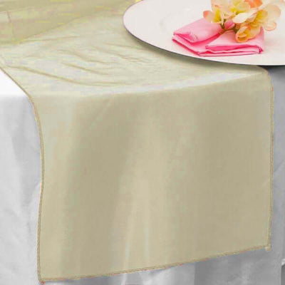 Elegant cream table runner on a dining table with pink napkins and flowers.
