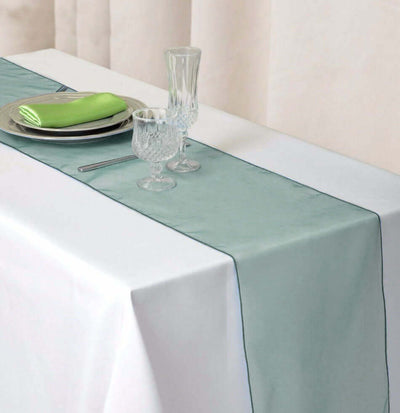 Elegant mint green table runner on a white tablecloth with glassware and napkins.