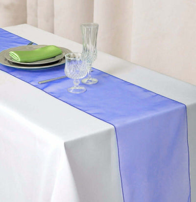 Lavender table runner on a white table with glassware and napkins.