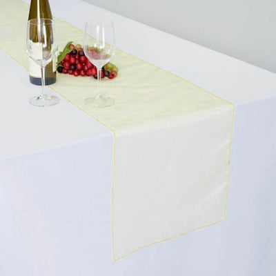 Elegant table runner with wine glasses and grapes on a white table.