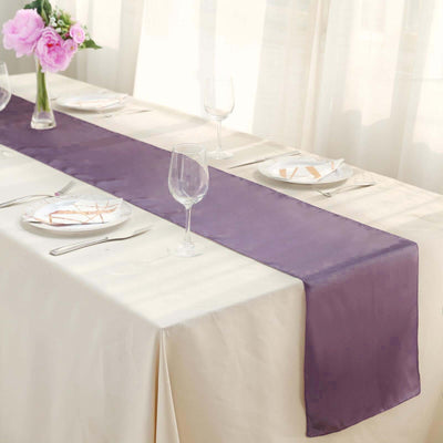Purple satin table runner on a dining table with elegant table settings.