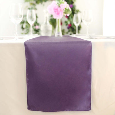 Purple satin table runner on a dining table with floral decor.