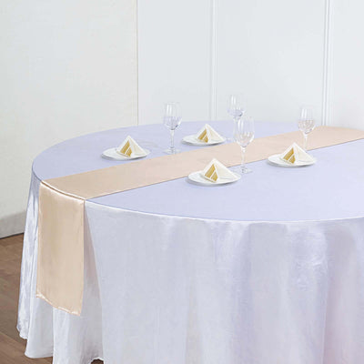 Elegant round table set with purple tablecloth and gold runner, decorated with plates and glasses.