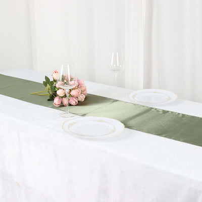 Elegant green table runner with plates and pink floral arrangement on a dining table.