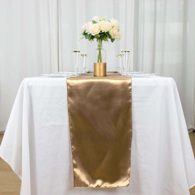 Elegant gold table runner on a white table with floral centerpiece.