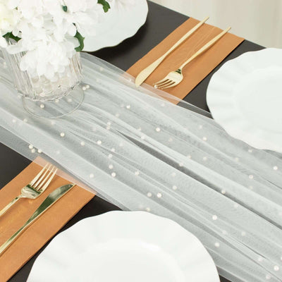 Elegant table setting with white plates, gold utensils, and decorative runner.