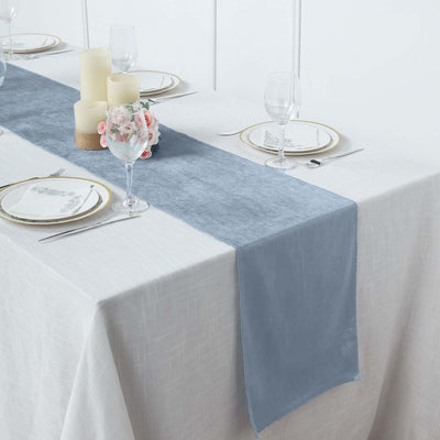 Elegant light blue table runner on a dining table set with plates and glasses.