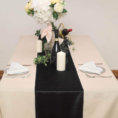 Elegant dining table setup with black runner, candles, and floral centerpiece.