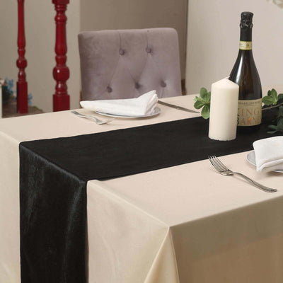 Elegant black table runner on a beige table setting with candles and wine.