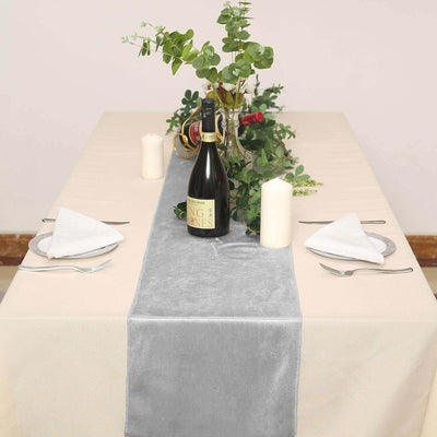 Elegant table setting with gray runner, wine, candles, and greenery decor.
