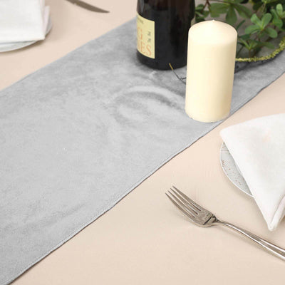 Gray table runner on a dining table with candle and fork.