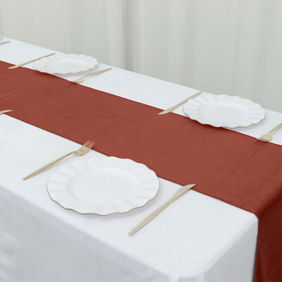 Elegant table setting with a rust-colored runner and white scalloped plates.