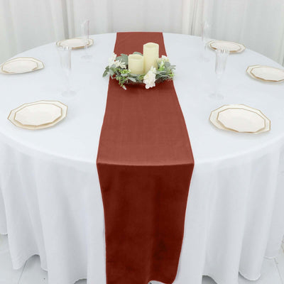Rustic burgundy table runner on a round table set for dining.