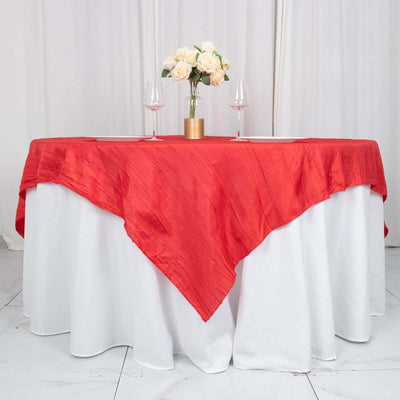Red tablecloth draped elegantly over a round table with floral centerpiece and wine glasses.