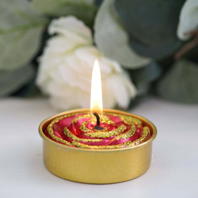 Gold and pink decorative candle with a flame, surrounded by greenery.
