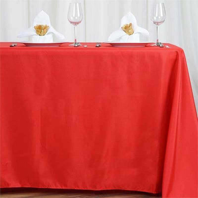 Red tablecloth elegantly draped over a table, set for an occasion.
