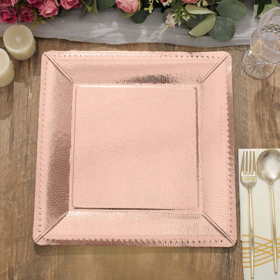 Rose gold textured charger plate on a wooden table with floral accents.