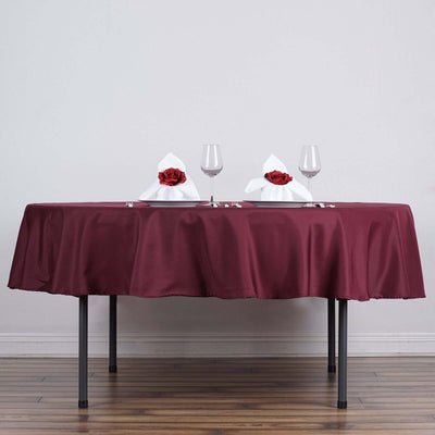 Elegant table setting with burgundy tablecloth and decorative napkins.