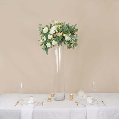 Elegant flower arrangement in a tall glass vase on a dining table.