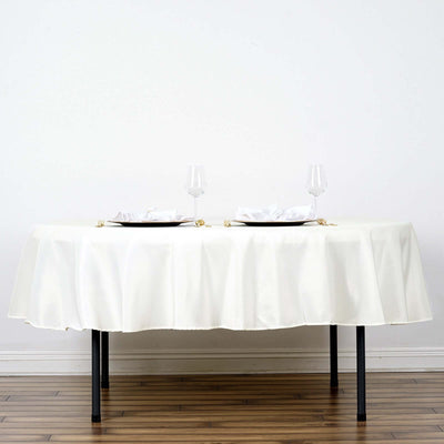 Elegant white tablecloth draped over a table set for two with plates and glasses.